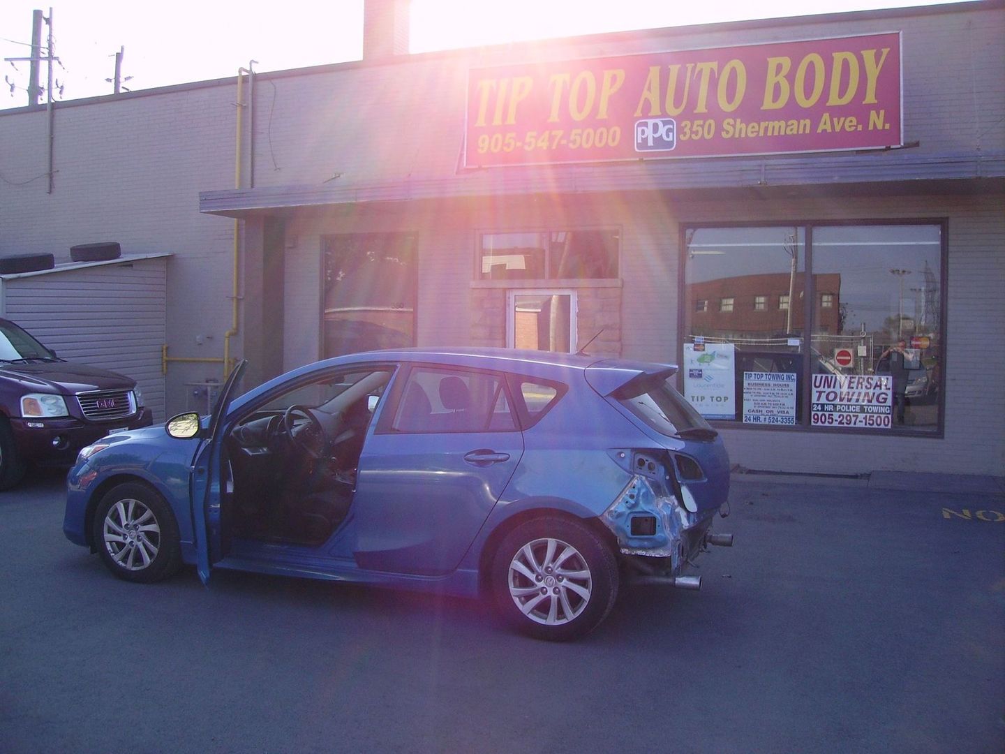 If you have a wrecked bumper like this car, bring it into our shop today! Small car with wrecked bumper parked in front of Tip Top Auto Body awaiting repairs