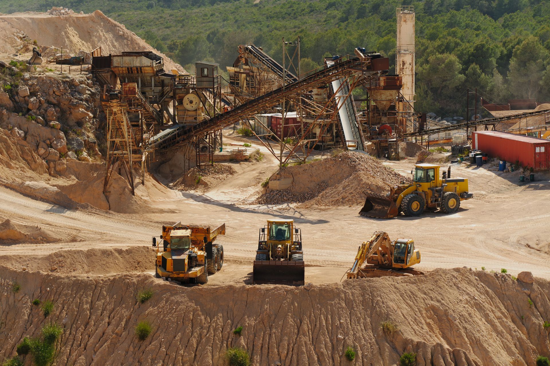 Heavy mining site with bulldozers, trucks, and an ore conveyor in a dusty quarry