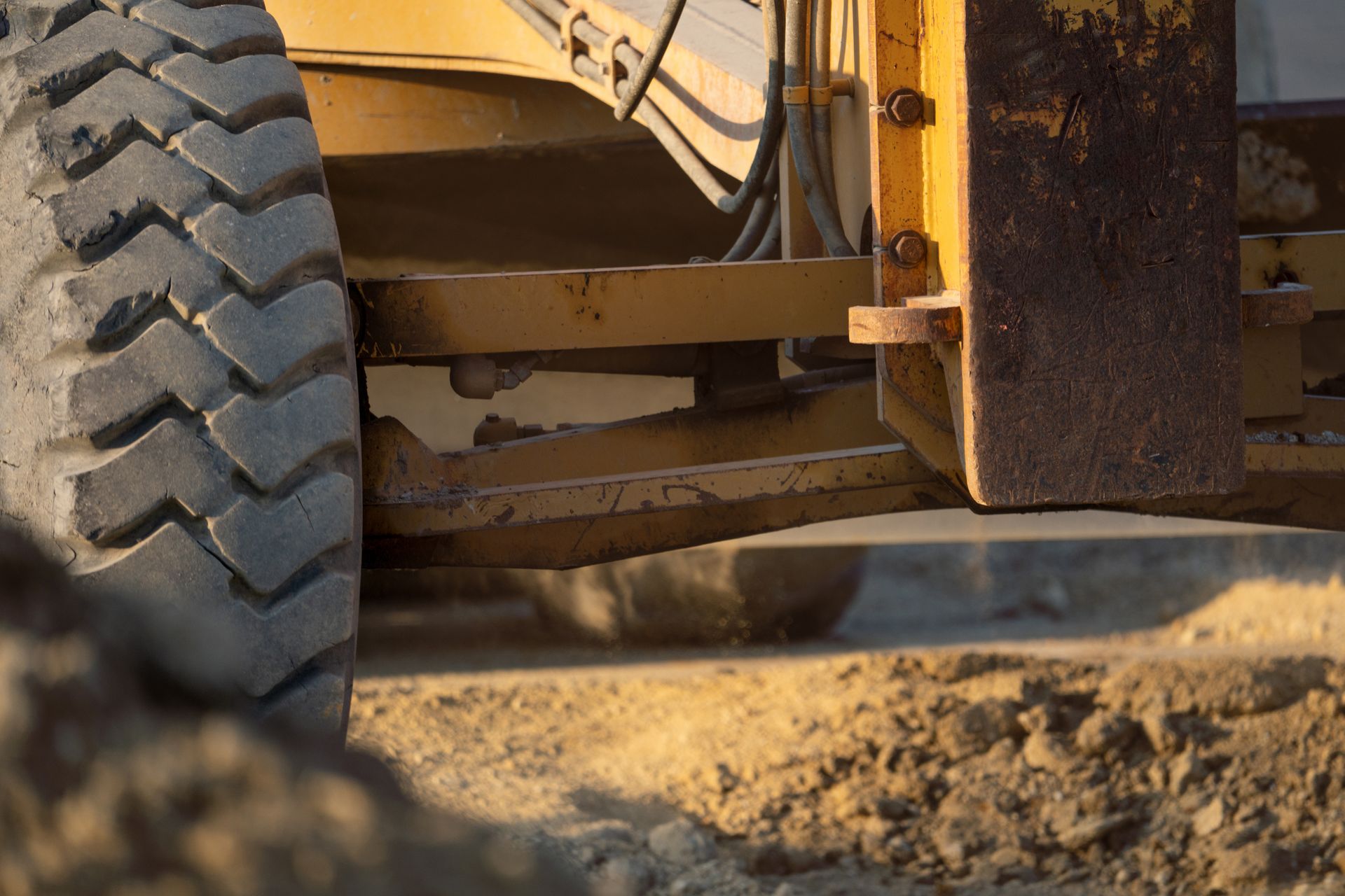 Close-up of a heavy vehicle tire rolling over dusty ground at a construction site