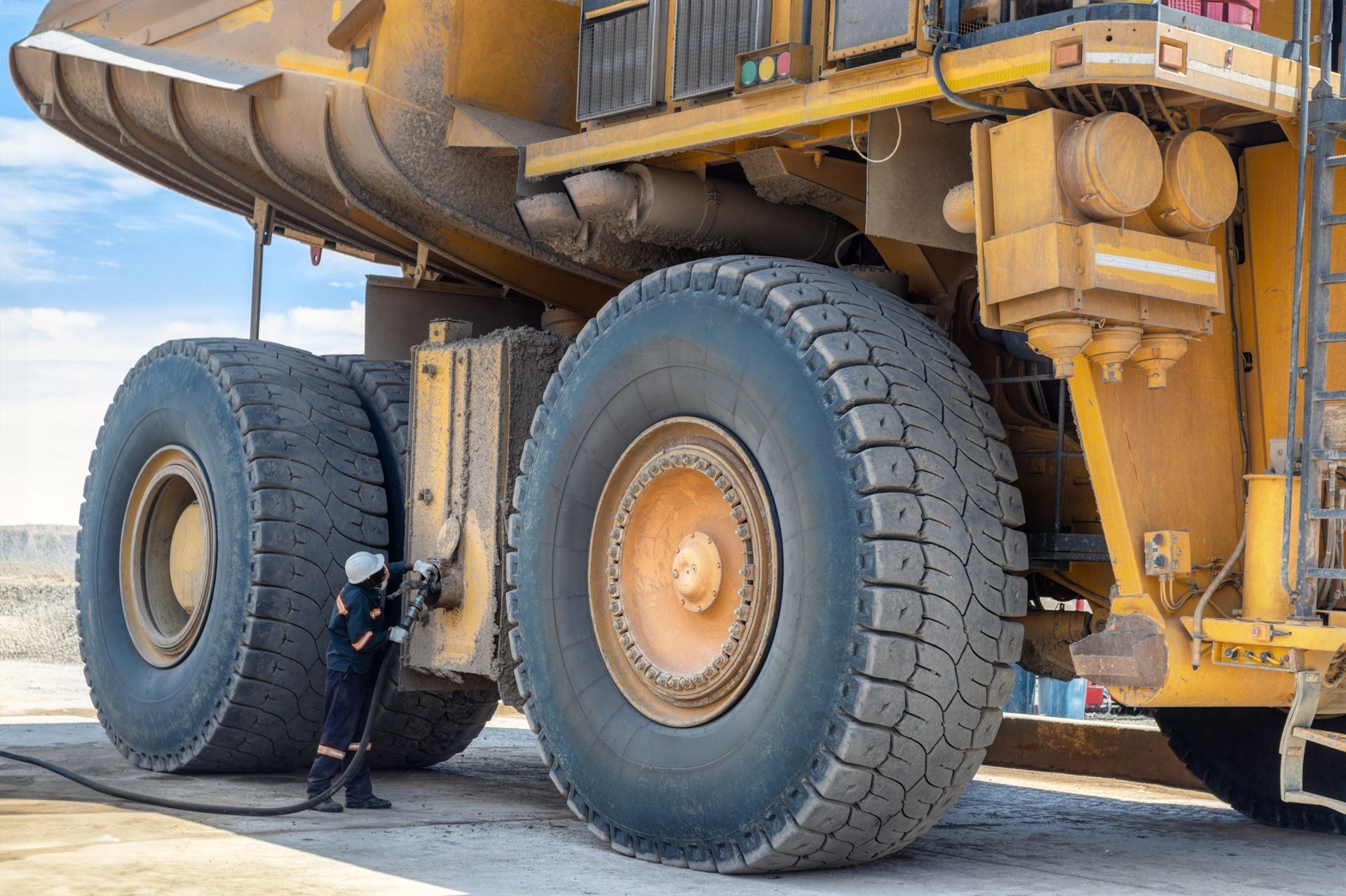 Worker standing beside a massive yellow mining truck tire in a desert setting
