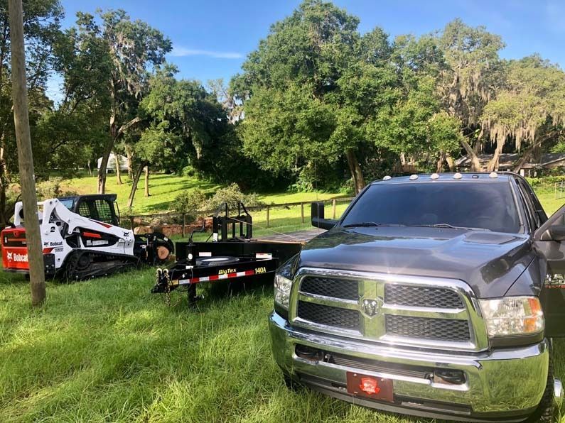 Pickup truck and skid steer in a grassy park on a sunny day