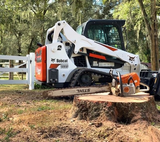 Bobcat skid steer with stump grinder cutting a large tree stump in a wooded yard