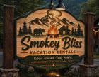 Smokey Blus vacation rentals sign with mountains, pine trees, bear, cabin, and campfire at dusk