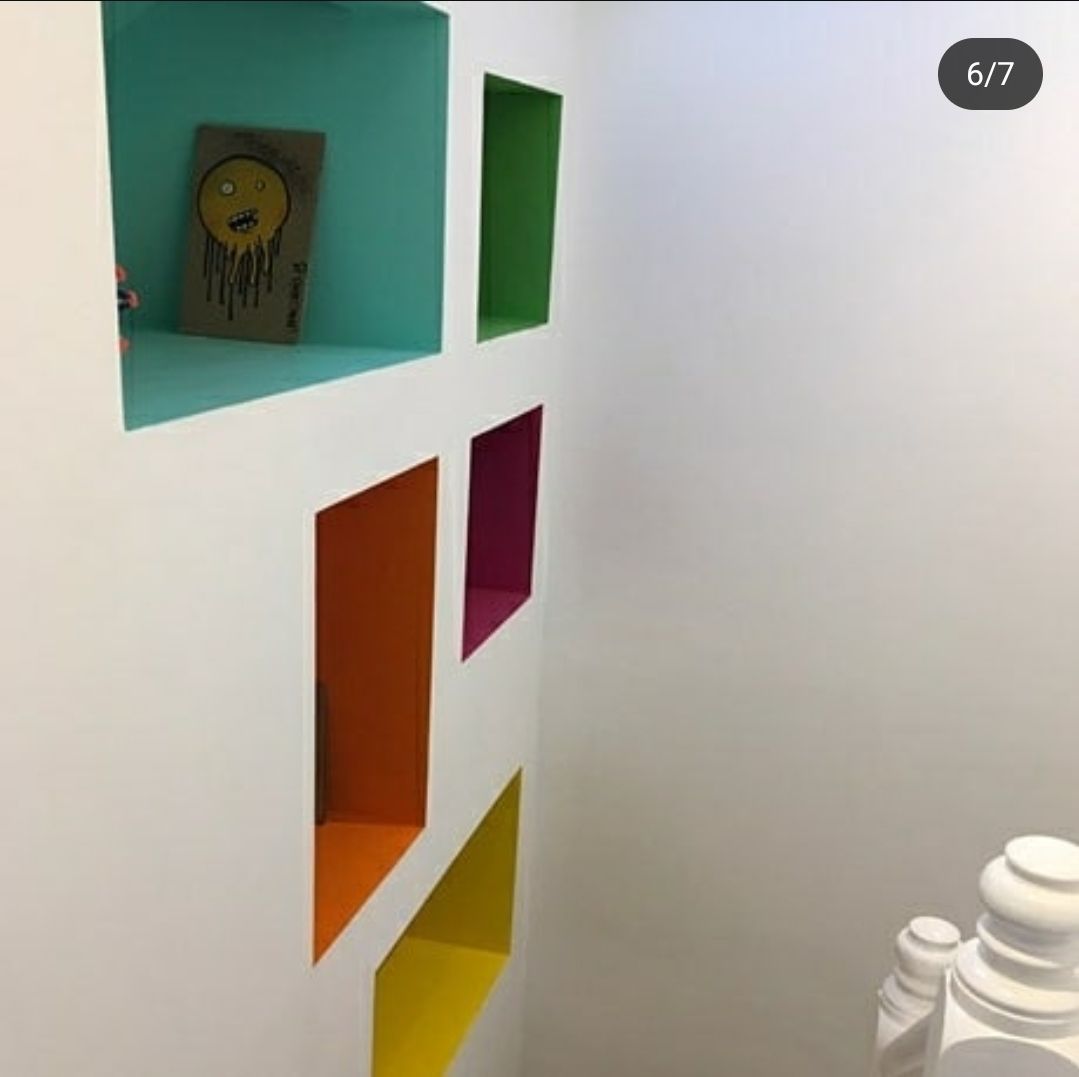 A white wall with a bunch of colorful shelves on it