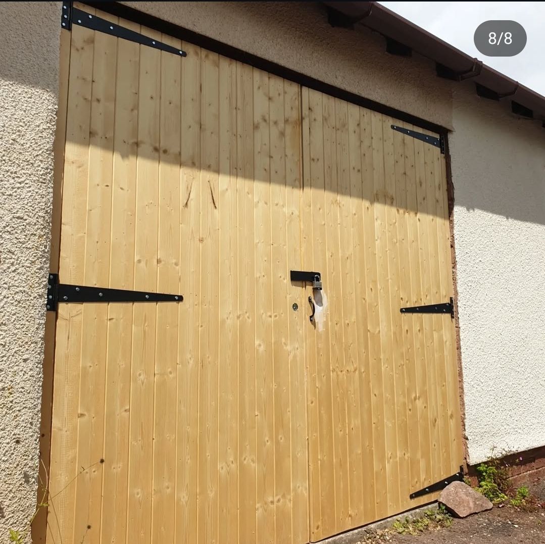 A wooden garage door with black hinges and a lock