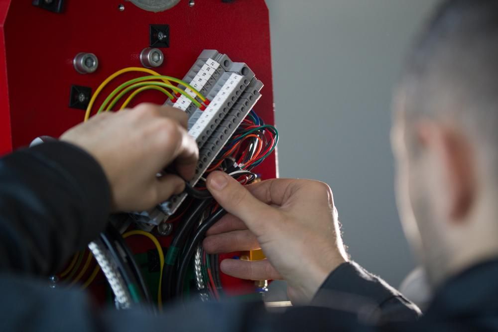 A Man Is Working on A Machine with Wires and Connectors — KARM Electrical Services In Ashtonfield, NSW