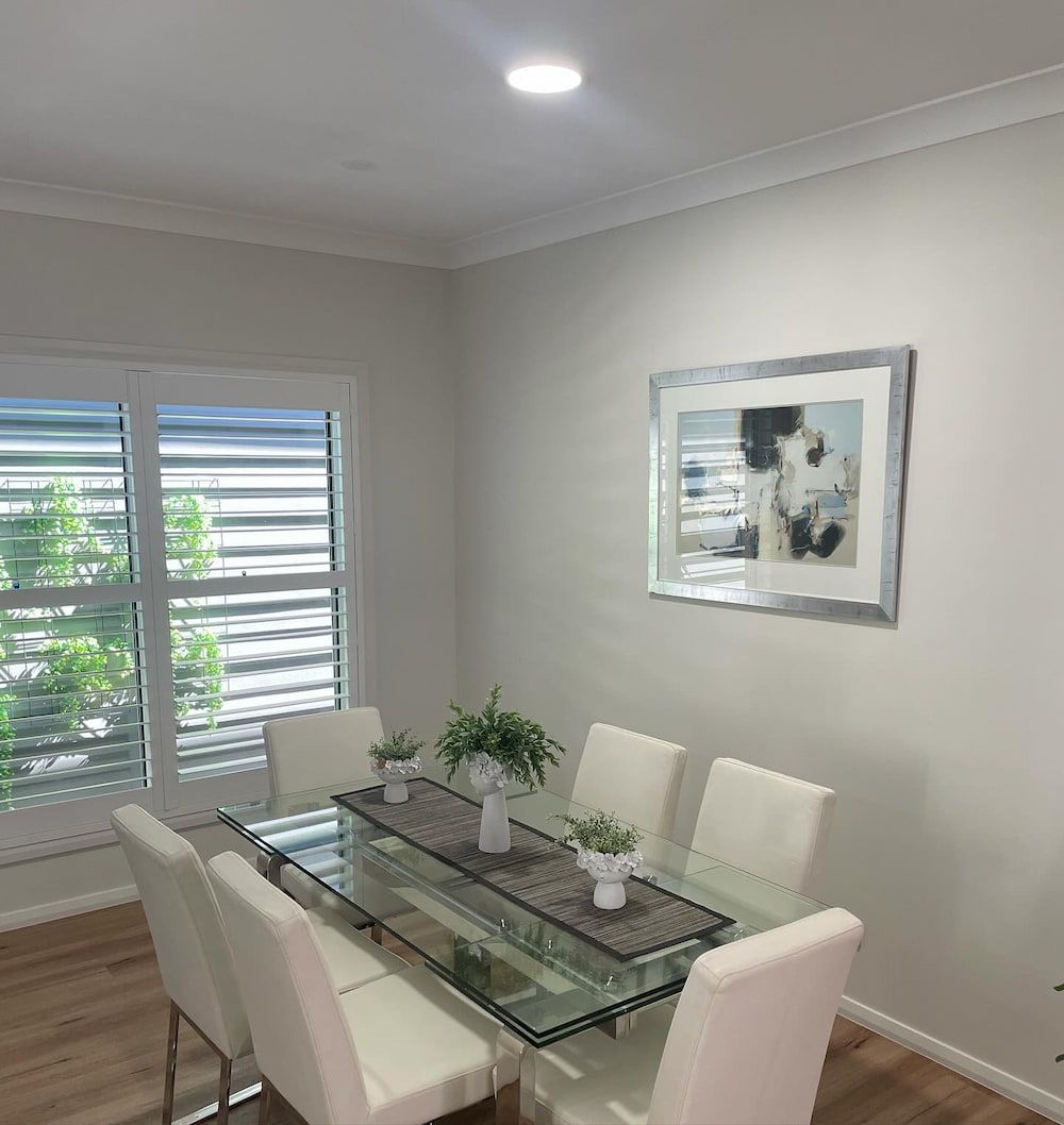 A Dining Room With A Glass Table And Chairs And New Light — KARM Electrical Services In Medowie, NSW