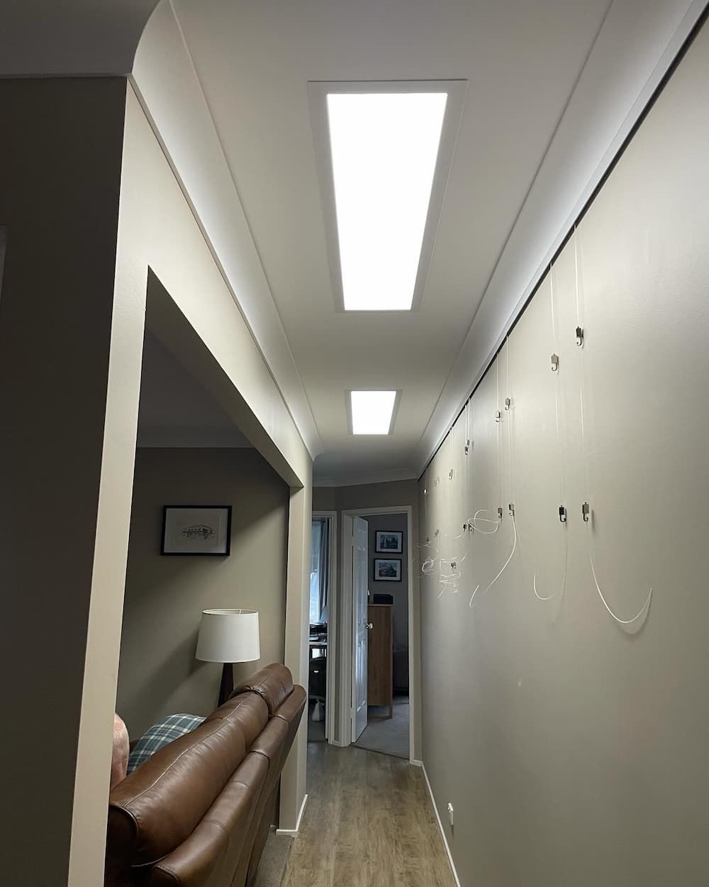 A Long Hallway With A Couch And A Lamp Being Installed — KARM Electrical Services In Medowie, NSW
