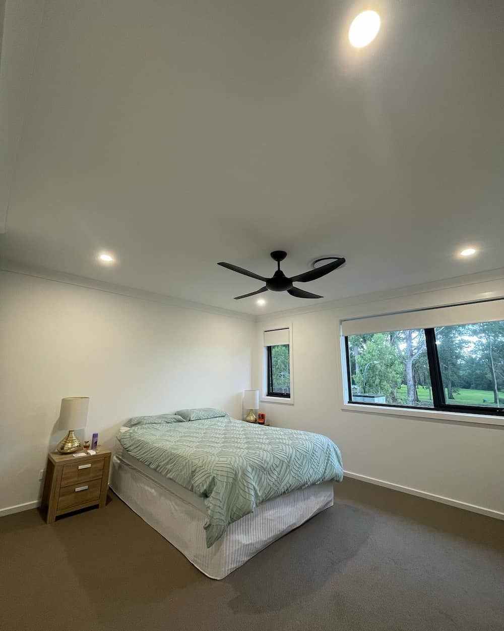 A Bedroom With A Bed, Nightstand, Lamp And Ceiling Fan — KARM Electrical Services In Soldiers Point, NSW