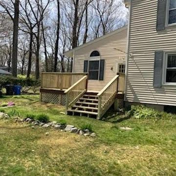 A house with a wooden deck and stairs in front of it.