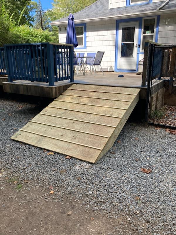 A wooden ramp leading to a deck next to a house.