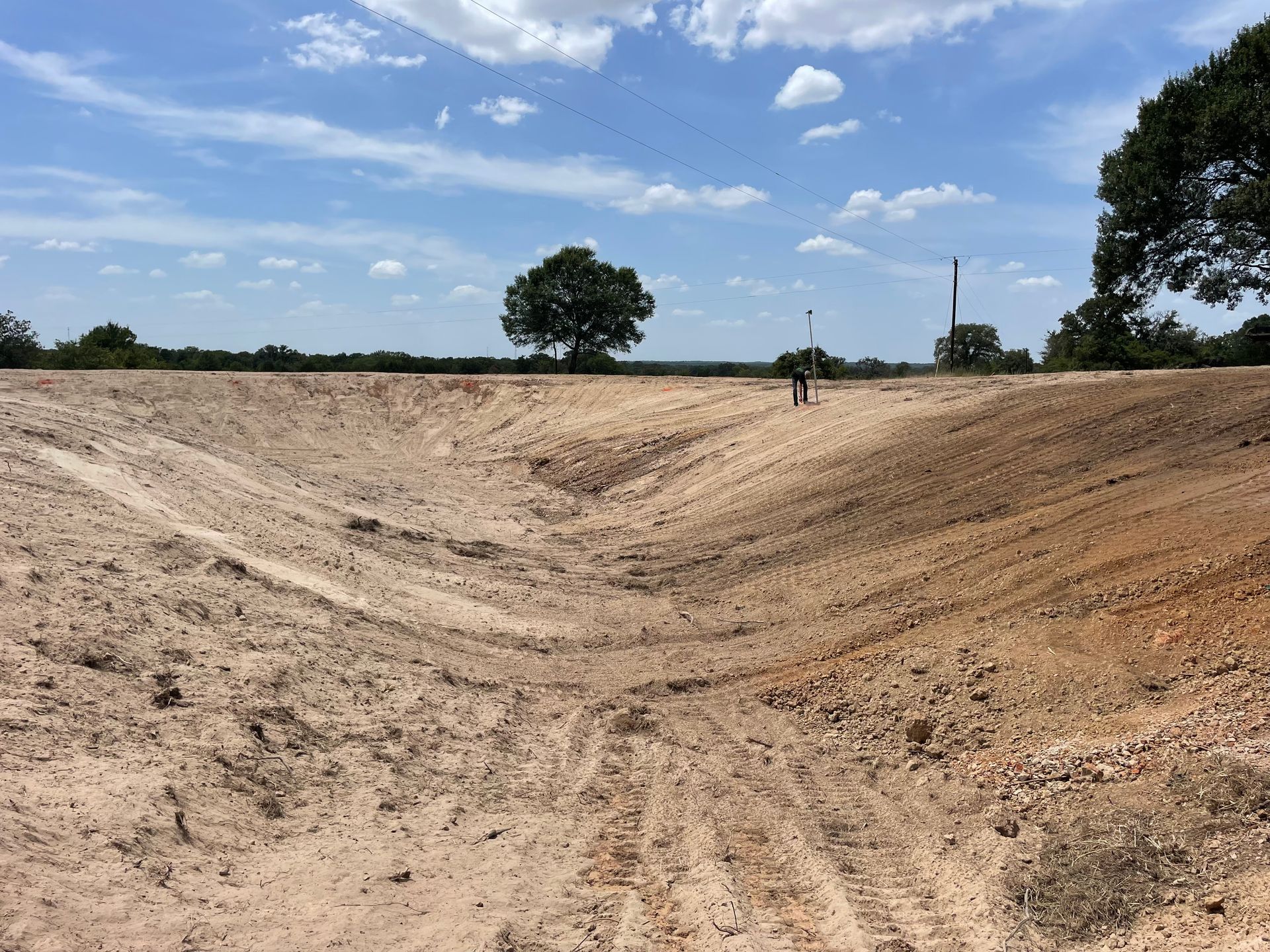 A wide, dry ditch cut into the earth, with a person standing near the center.
