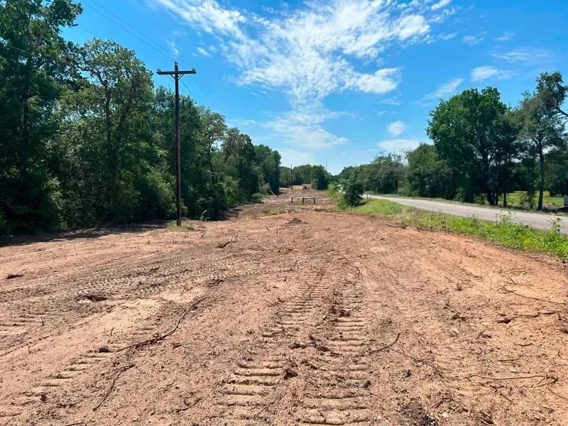 A dirt road with a telephone pole in the middle of it