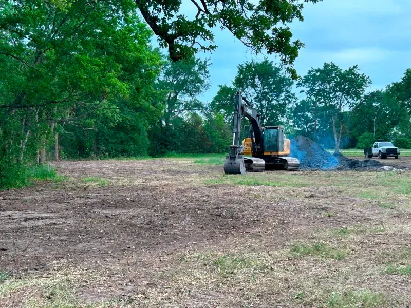 An excavator is digging a hole in the middle of a field.