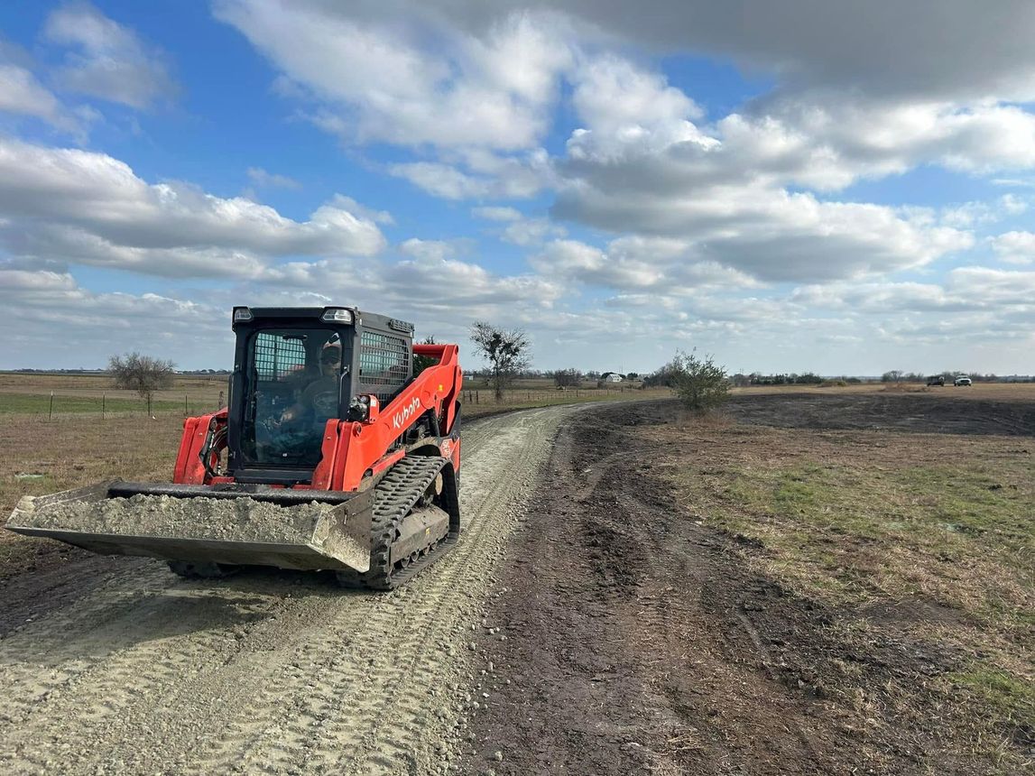 A bulldozer is driving down a dirt road in a field.