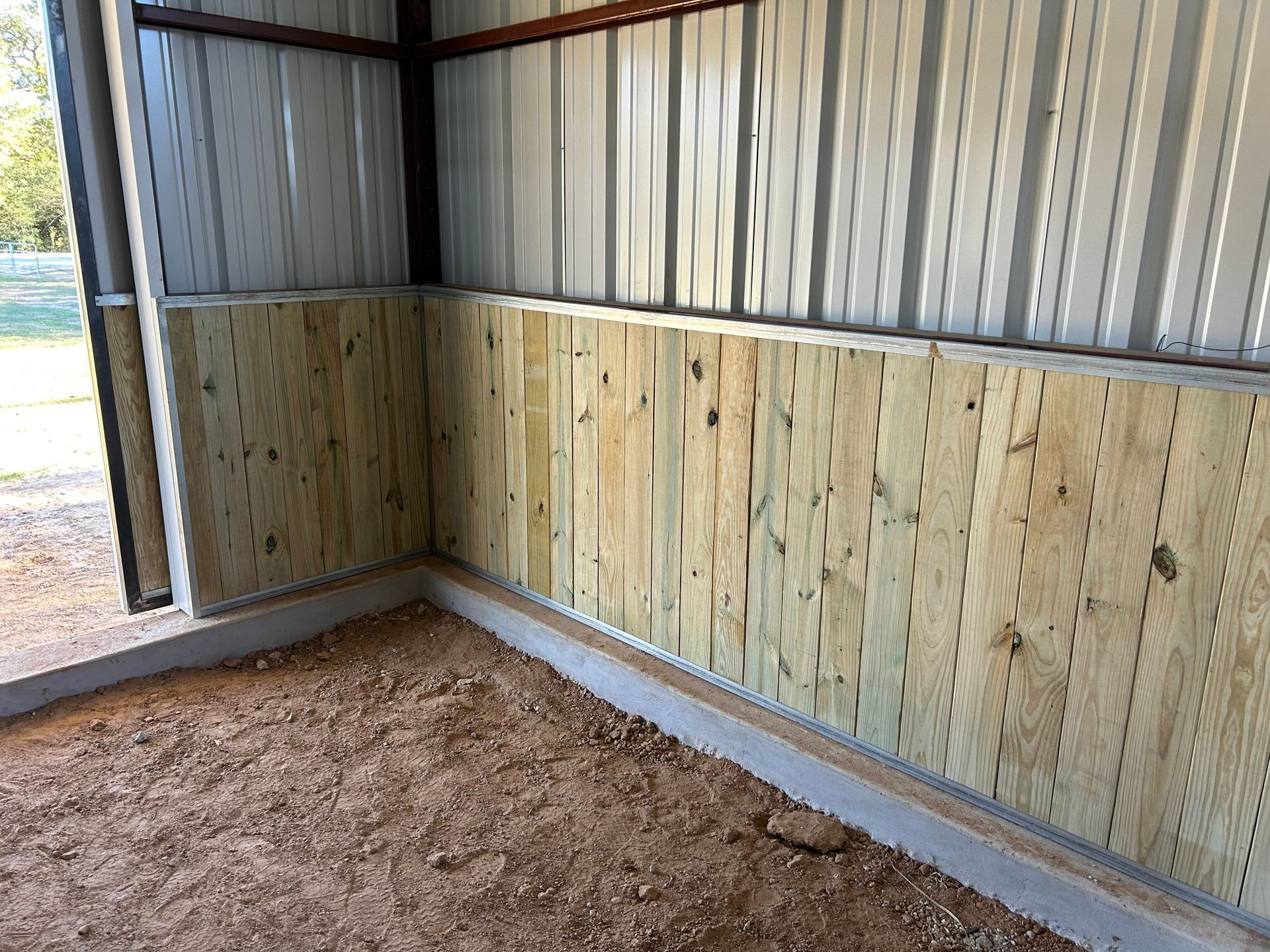 Interior of a metal-walled structure with wood paneling on lower walls, on a concrete base.