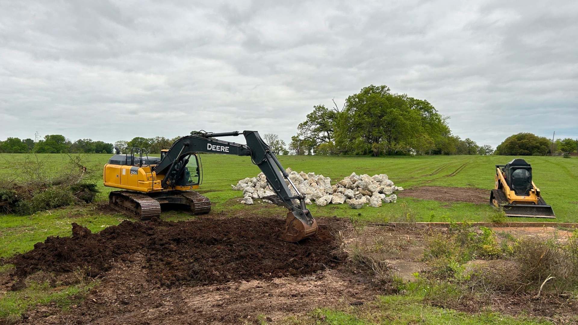 A yellow excavator is digging a hole in a field.
