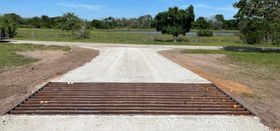 A gravel road with a metal barrier on the side of it.
