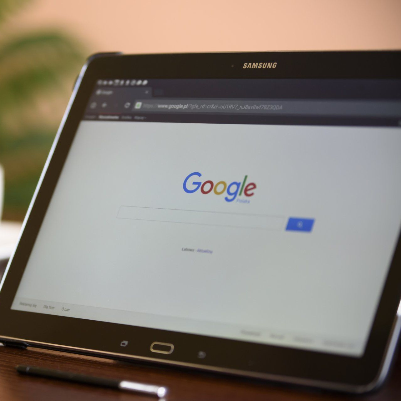 A black Samsung tablet displays the Google search engine. A stylus sits below the screen.