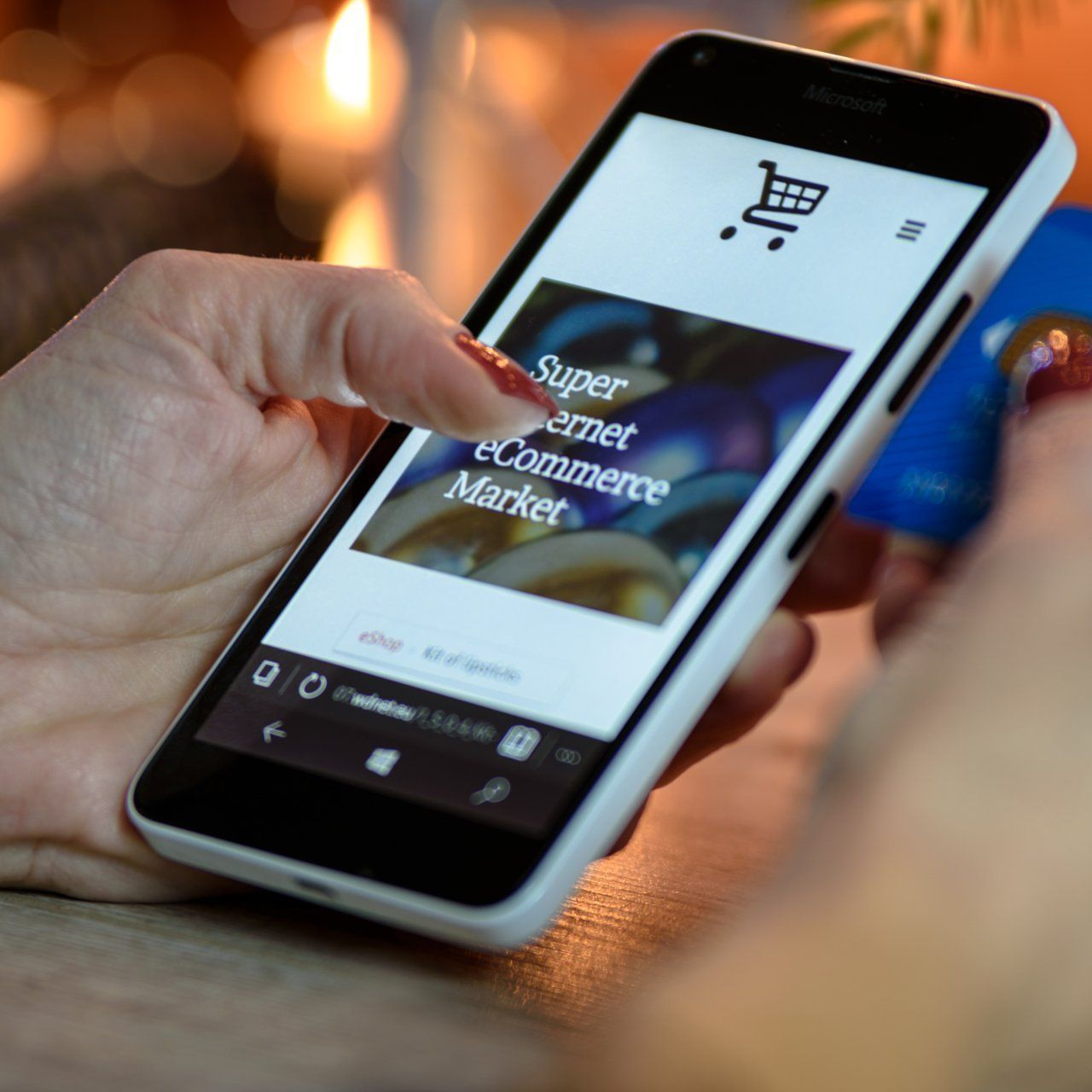 Woman using phone to shop online: e-commerce site visible on screen, shopping cart icon, credit card held.