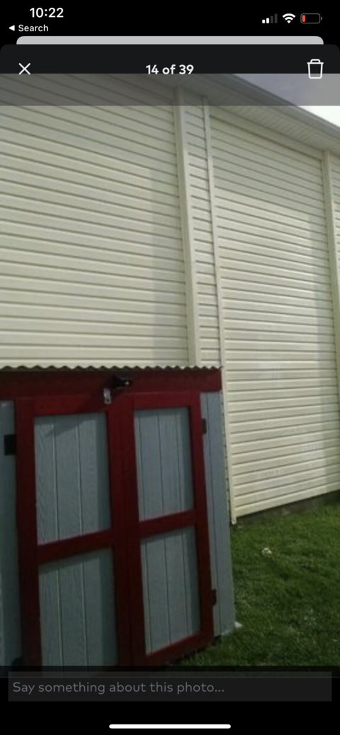 Red window shutters below white horizontal siding on a house exterior.