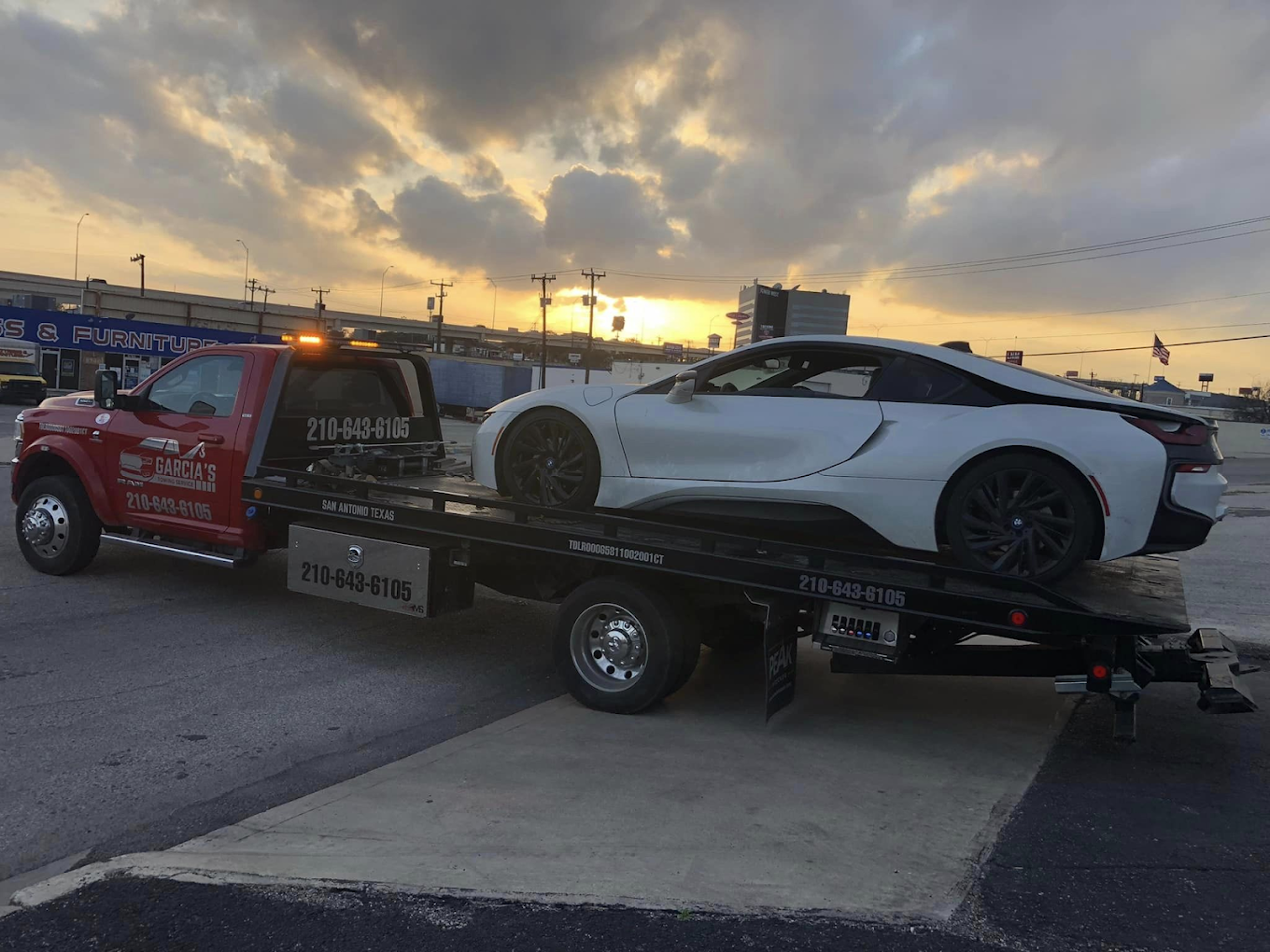 A white sports car is being towed by a tow truck.