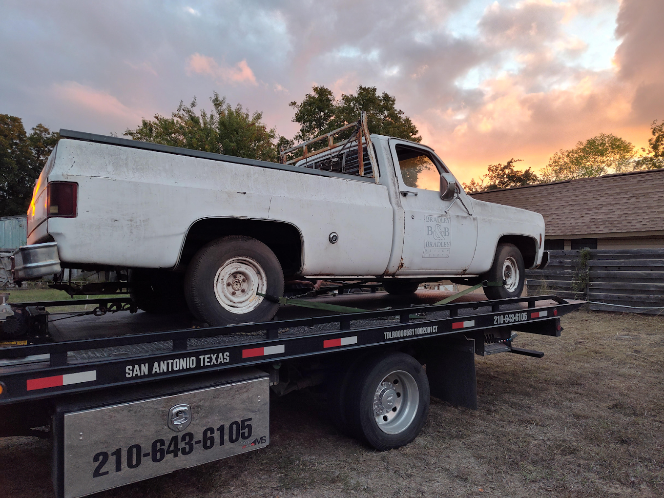A white truck is sitting on top of a tow truck.
