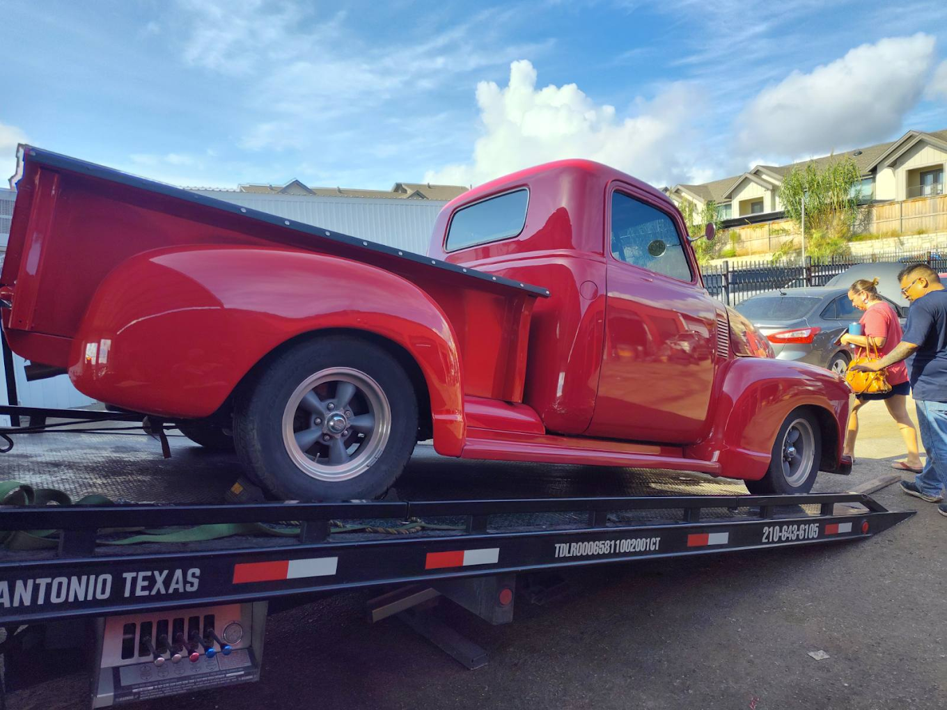 A red truck is sitting on top of a tow truck.