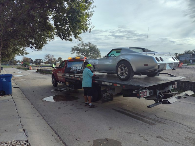 A silver car is being towed by a tow truck