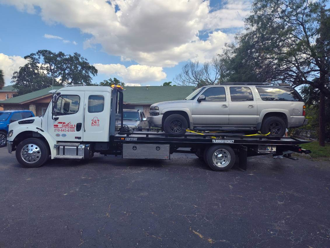 A tow truck is carrying a silver suv on the back of it.