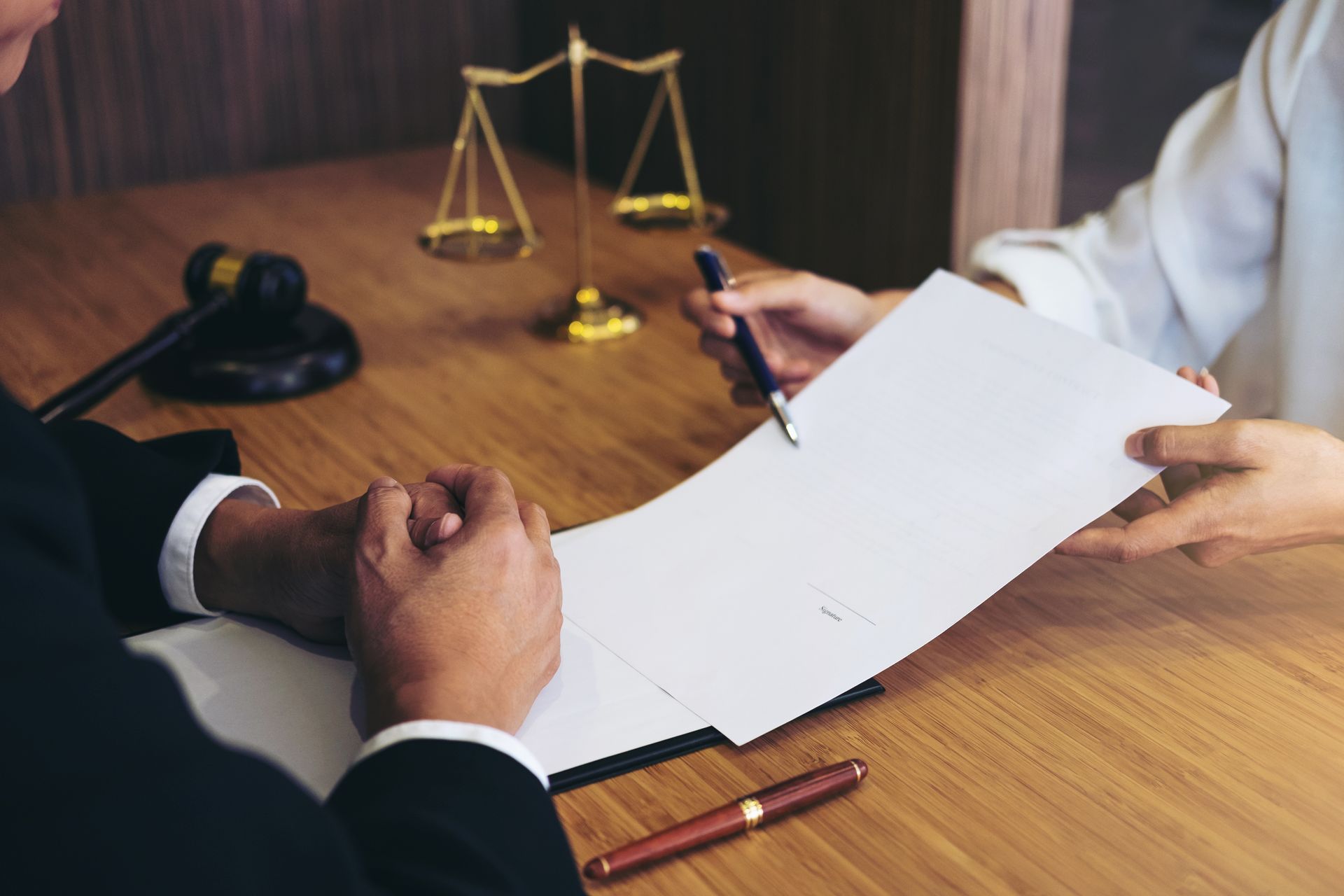 Attorney and client review paperwork; gavel and scales in background