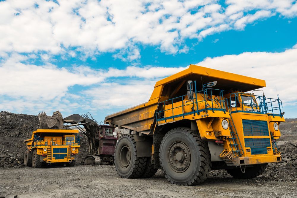Two Yellow Dump Trucks Are Parked Next to Each Other in a Dirt Field — BOEX Tyres And Performance in Bowral, NSW