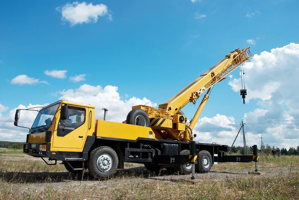 A Yellow Truck With a Crane Attached to It is Parked in a Field — BOEX Tyres And Performance in Bowral, NSW
