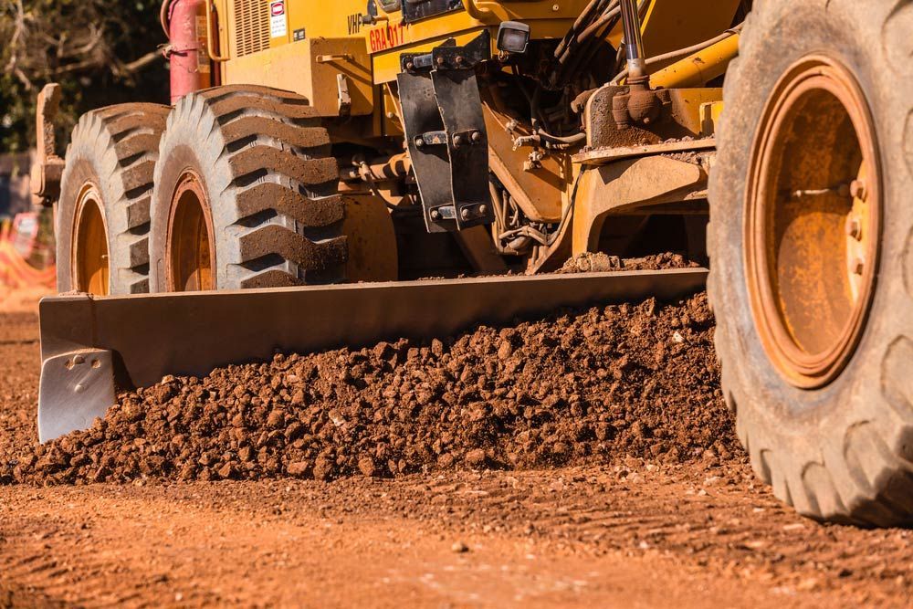 A Bulldozer is Moving Dirt on a Dirt Road — BOEX Tyres And Performance in Bowral, NSW
