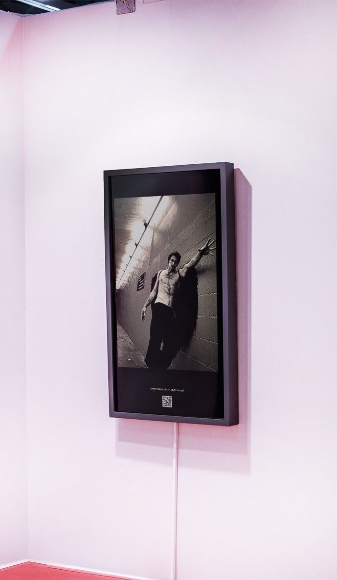 Framed black-and-white portrait on a pale pink wall with a cable hanging below