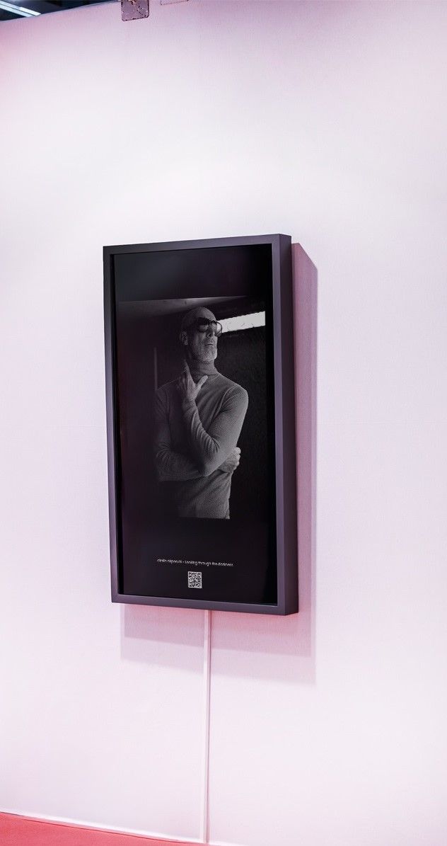 Framed black artwork on a white wall, showing a grayscale figure in profile and lit from the side.