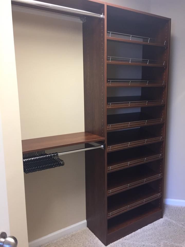 Dark wood closet organizer with a hanging rod, a shelf, and a tall column of open shelves featuring wire basket inserts.