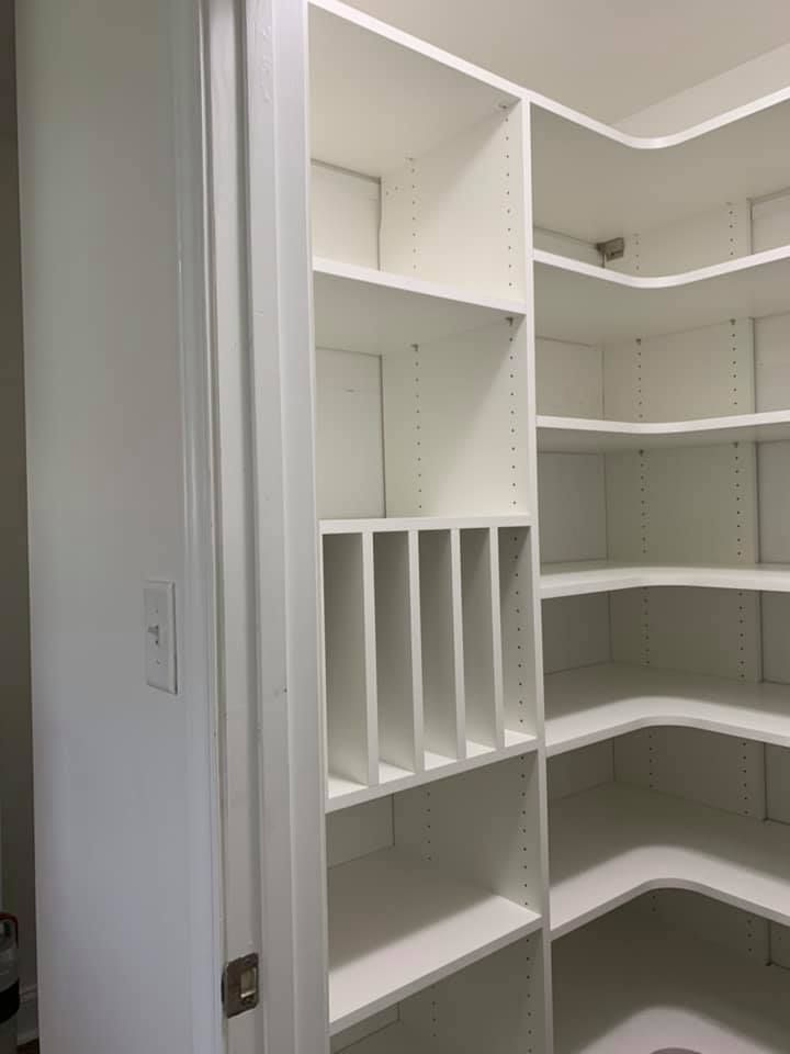 White, L-shaped pantry shelving with vertical dividers for standing items, viewed from the doorway.