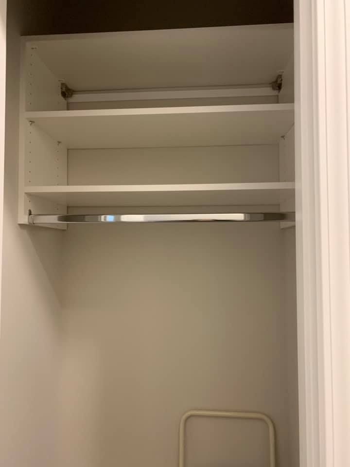 A white closet interior featuring a top shelf, a middle shelf, and a metal clothing rod hanging below.