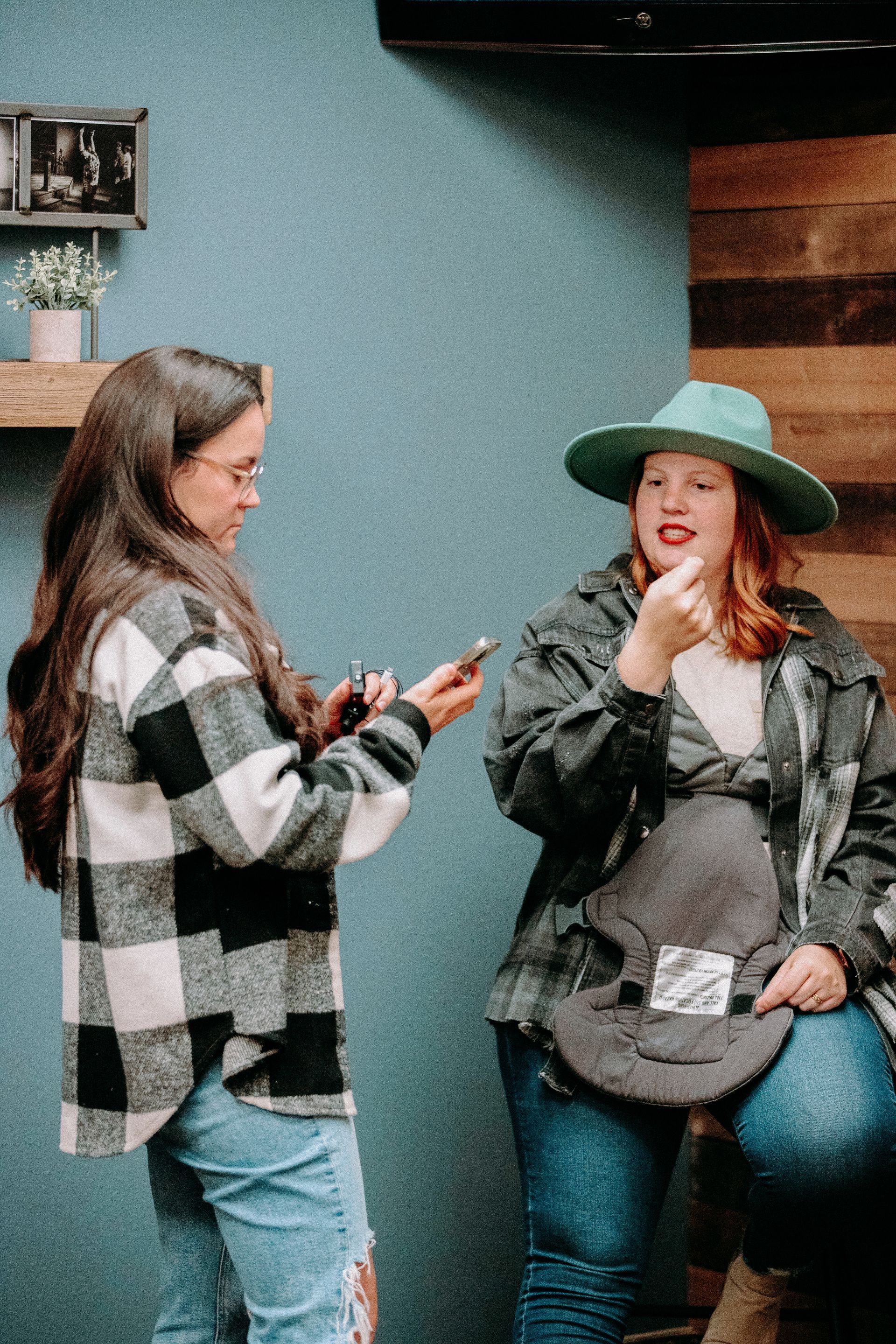 Two women are standing next to each other looking at their phones.