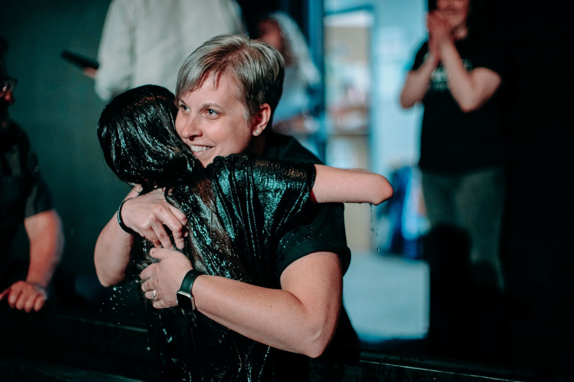 A woman is hugging a child who is covered in water.