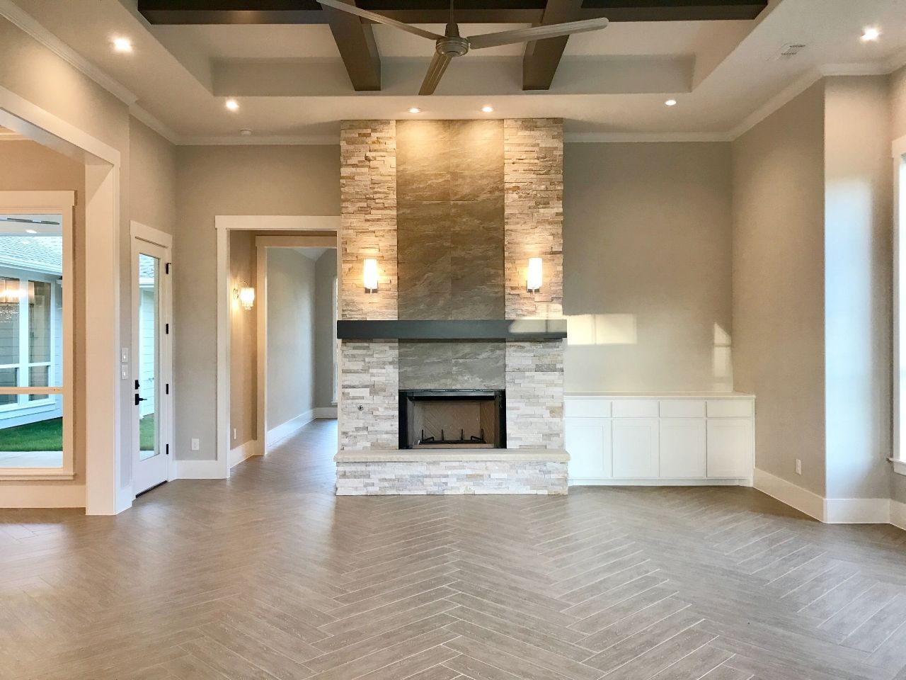 Living room with stone fireplace, wood floors, recessed lighting, and built-in cabinet.