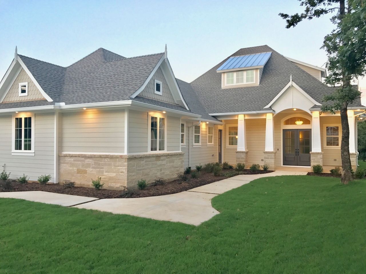 Suburban home with light gray siding, stone accents, and manicured lawn.