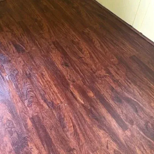 Dark wood floor with reddish-brown streaks and a white wall edge in the corner.