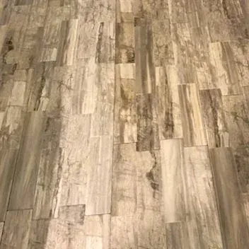 Close-up of worn gray-brown wood plank flooring with a distressed, weathered pattern