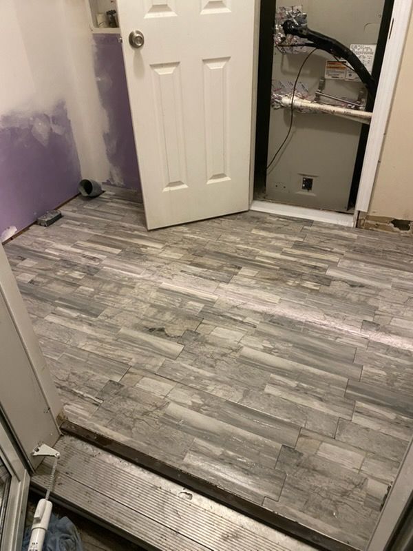 Partially renovated room with gray wood-look flooring, purple walls, and an open closet doorway