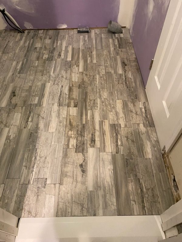 Small room with gray wood-look flooring, purple walls, and a white doorway threshold.