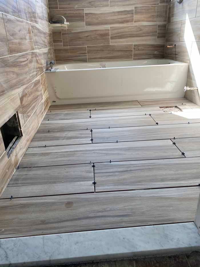 Bathroom under renovation with beige tile walls and unfinished wood-look floor planks