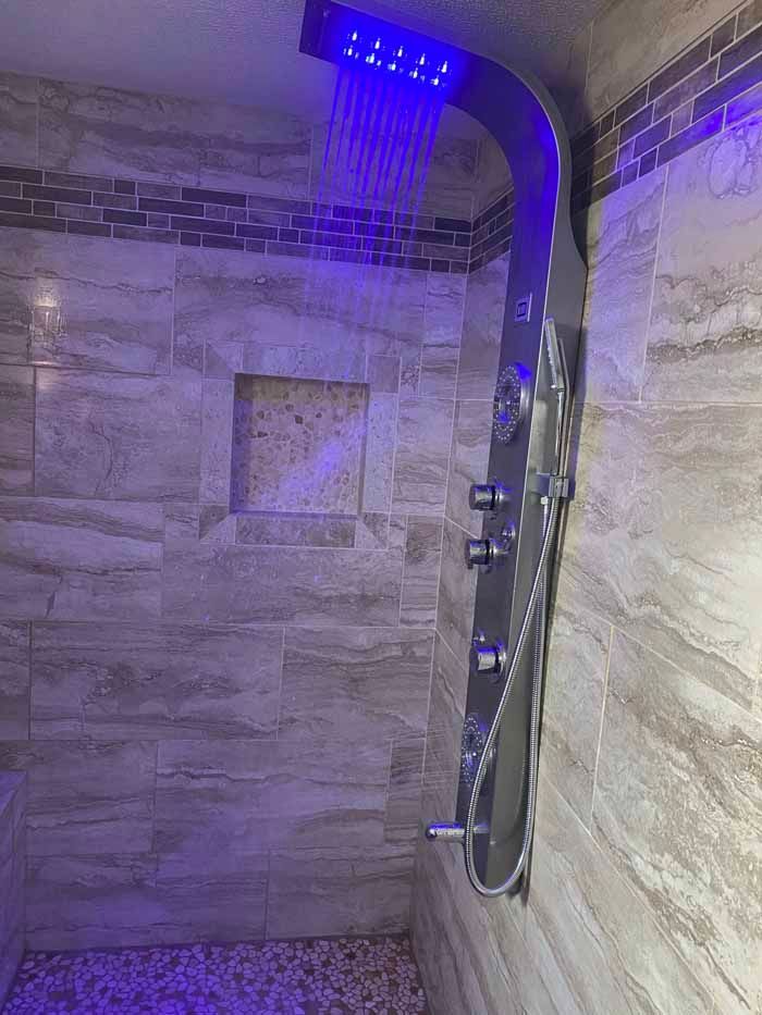 Stone-tiled shower with blue LED rainfall head and handheld sprayer