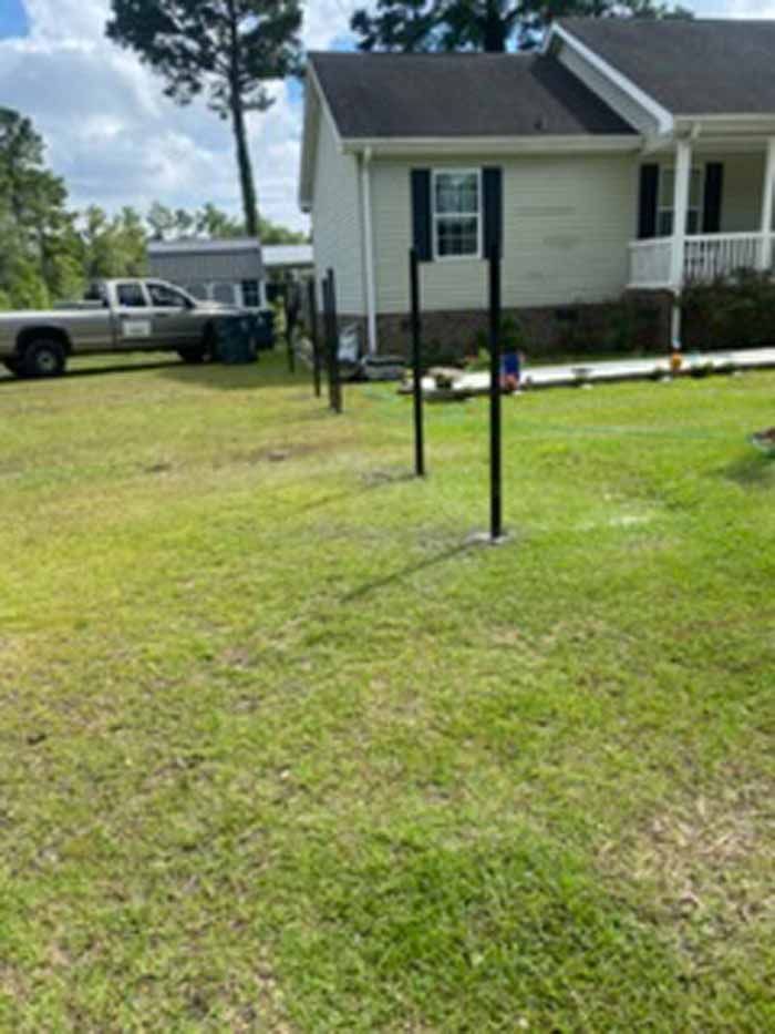 Backyard lawn with a black metal post in front of a house and parked truck